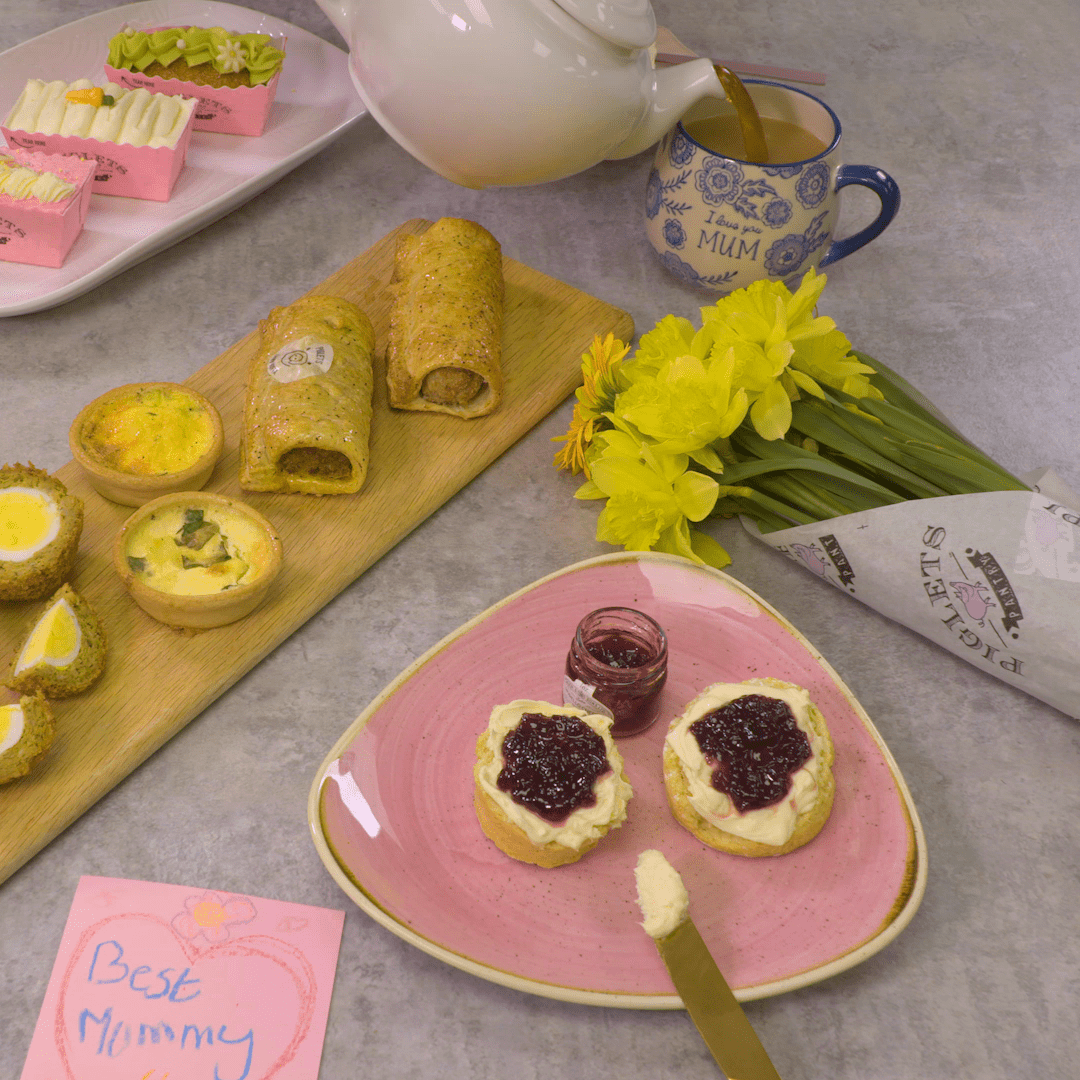 scotch eggs, scones, cakes, sausage rolls and quiches on plates with chocolate coins, pink napkins and a gold bauble