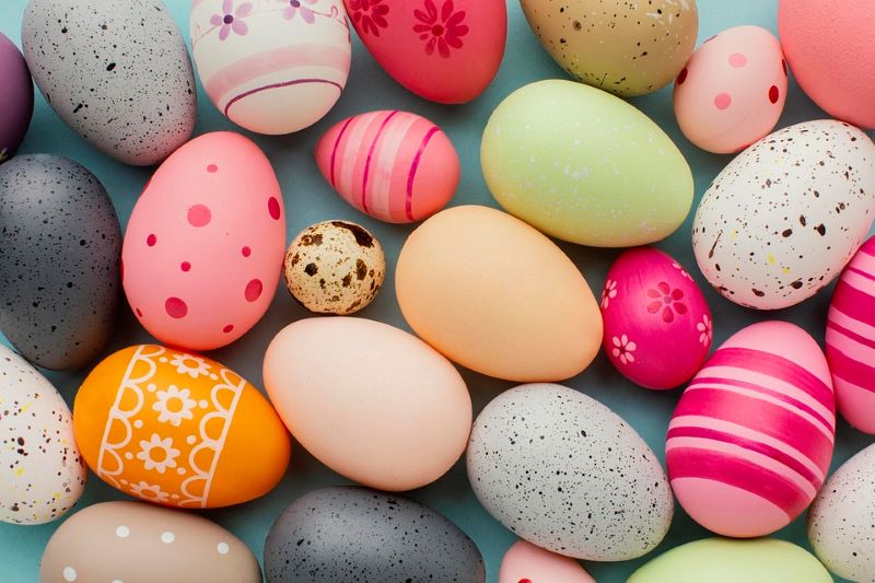 Aerial view image of various brightly coloured easter eggs on a blue background