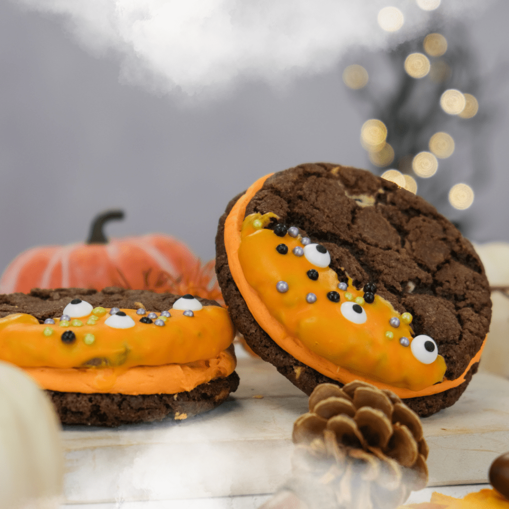 Two halloween cookie sandwiches surrounded by spooky decorations