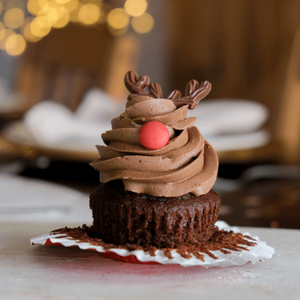 A reindeer shaped cupcake on a white wooden board.